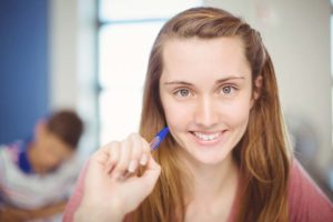 Portrait of smiling school girl doing homework in classroom